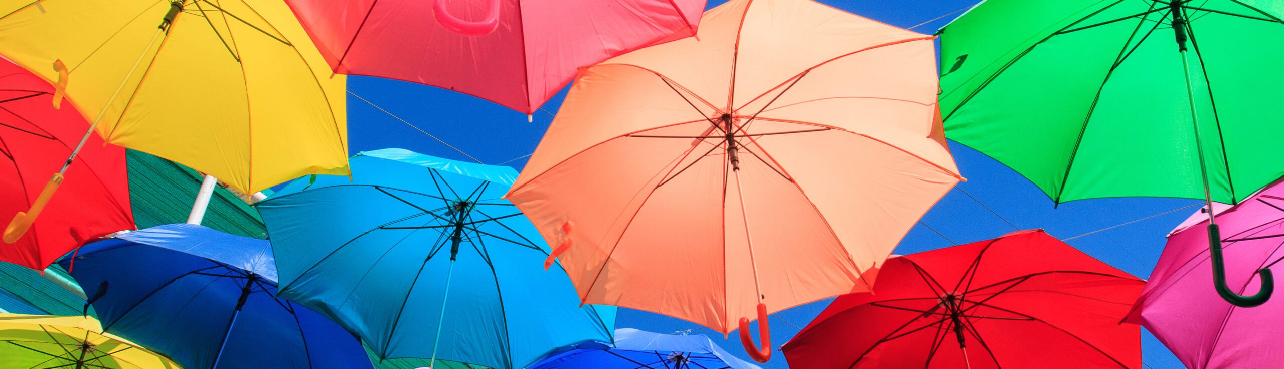 PICA Marketing Group homepage slider. Image of different colored umbrellas against blue sky.